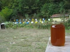 a jar of honey sitting on top of a wooden table in front of a field