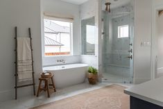 a bathroom with a tub, shower and stool next to a window in the wall