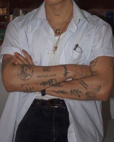 a man with tattoos on his arms and chest is posing for the camera while wearing a white shirt