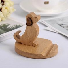 a wooden toy dog sitting on top of a white table next to flowers and magazines