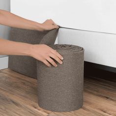 a person rolls up a roll of toilet paper on the floor next to a wall