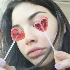 a woman holding two lollipops with hearts on them