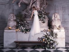 a woman in a white dress standing next to some statues