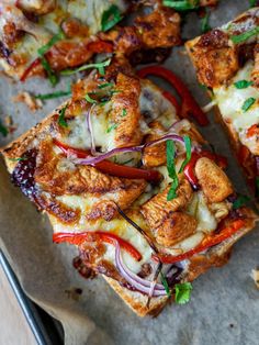 several slices of pizza with various toppings on a sheet of paper next to a fork