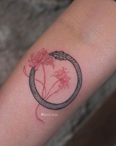 a woman's arm with a tattoo on it that has a snake and flowers in the center