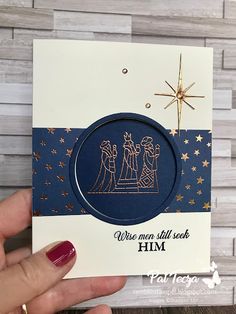 a hand holding up a card with a nativity scene in the center and stars on it