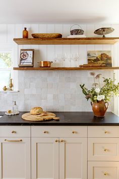 a kitchen with white cabinets and black counter tops, gold pulls on the cupboards