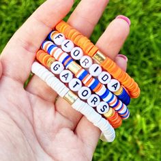 Show your fan pride with this awesome Florida Gators Bracelet Set! This 5 piece set is ideal for any female Gators fan looking for a stylish way to sport their team pride. Whether you’re attending a game day event or just strutting around town, these bracelets will help you show your team spirit and are sure to be your new go-tos when out and about! This set of five beautiful bracelets come in the perfect color combo – orange and blue – to proclaim your Gator love. Featuring a lightweight and st Florida Gator Bracelet, Heishi Bracelet Ideas Sports, School Spirit Crafts, Bracelet Maker, Heishi Bracelets, Team Bracelets, Sister Crafts, Bead Accessories, Heishi Bracelet