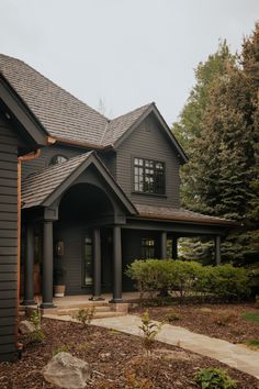 a large gray house surrounded by trees and bushes