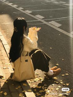 a woman sitting on the curb with her hand up to her face while holding an umbrella