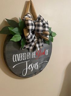 a wooden sign that says covered by the blood of jesus hanging on a wall next to a potted plant