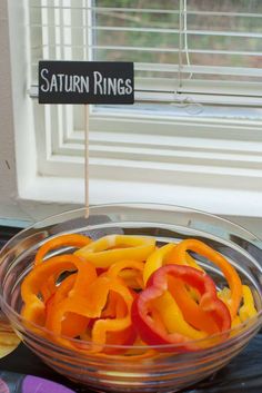 a bowl filled with sliced bell peppers next to a sign that says saturn rings on it