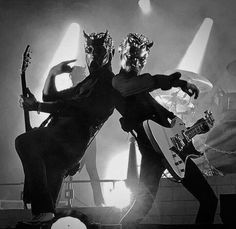 black and white photograph of two men playing guitars on stage with spotlights in the background