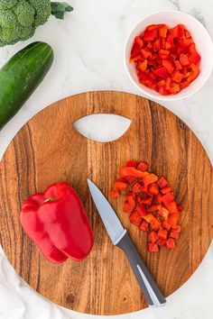 chopped red bell peppers on a cutting board next to a knife and broccoli