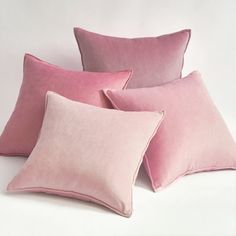 four pink velvet pillows stacked on top of each other in front of a white background