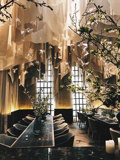 a dining room filled with lots of tables covered in white cloths and hanging from the ceiling