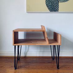 two wooden tables sitting on top of a hard wood floor next to a wall with a painting above it