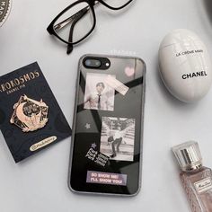 an assortment of personal items are displayed on a table with glasses, perfume and passport