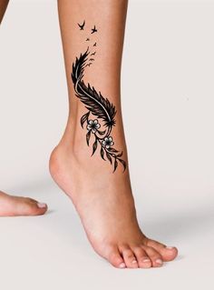 a woman's foot with a black feather tattoo on the side of her leg