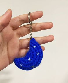 a hand holding a blue crochet keychain with white stars on it