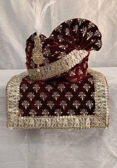 a red and gold brocaded purse with a feather on the top, sitting on a white surface