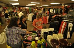 two women are shopping for items in a clothing store while another woman is looking at them