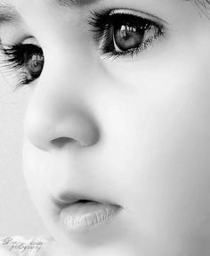 a close up of a child's face with blue eyes and long eyelashes, looking to the side