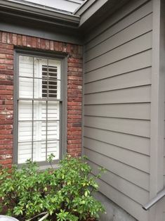 a window with shutters on the side of a brick building next to a potted plant