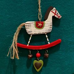 a wooden rocking horse ornament hanging on a green wall with bells and hearts