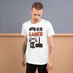 This gamer T-shirt features hand illustrated vintage gaming controllers. The tee makes a fun gift for any gamer that you know. The shirts are 90% combed and ring-spun cotton, 10% polyester. Fabric weight is 4.2 oz (142 g/m2) with pre-shrunk fabric. See our Apparel Sizing Guide for unisex adult T-Shirt sizing. Gamer Style Cotton T-shirt With Logo Print, Gamer Style Cotton T-shirt With Screen Print, Gamer Cotton T-shirt Pre-shrunk, Pre-shrunk Cotton Gamer T-shirt, White Cotton Gamer T-shirt, Casual Short Sleeve T-shirt For Gaming Events, Gamer Style Screen Print T-shirt For Streetwear, Cotton Gamer T-shirt For Streetwear, Crew Neck T-shirt With Graphic Print For Gaming Events