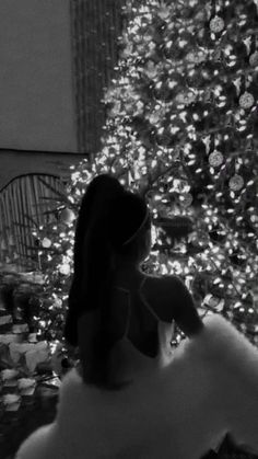 a woman standing in front of a christmas tree