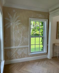 an empty room with wood floors and wallpaper on the walls, painted in shades of beige