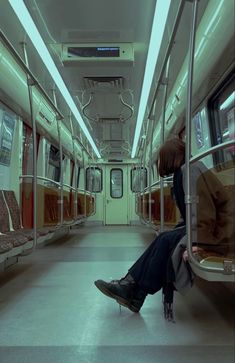 a person sitting on a subway car with their legs up against the wall and looking down