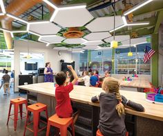 children are sitting at the bar in an open area with colorful lights and decorations on the ceiling