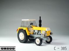 a lego model of a yellow tractor on a gray background with text below it that reads,