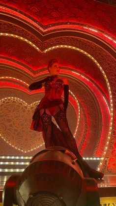 a woman standing on top of a giant object in front of a red and white background