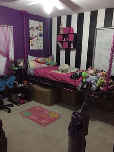 a bedroom with black and white stripes on the walls, pink bedding, and purple accessories