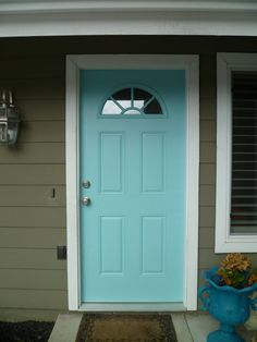 a blue front door on a house with white shutters and flower pot in front