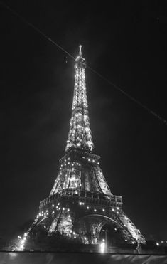 the eiffel tower lit up at night in black and white with lights on it