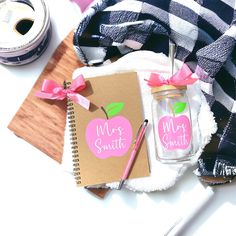 a notebook and pen sitting on top of a table next to a jar with an apple