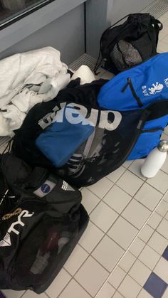 several duffel bags sitting on the floor in front of a store window with their lids open