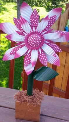 a pink and white paper flower sitting on top of a wooden table