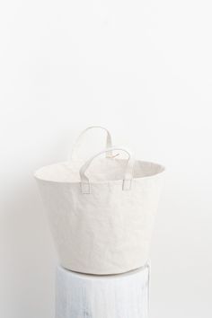 a white tote bag sitting on top of a stack of wooden blocks in front of a white wall