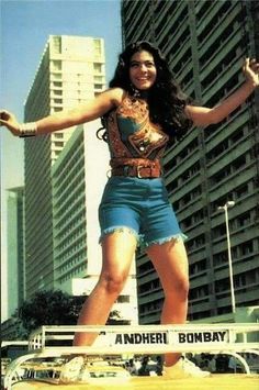 a woman standing on top of a skateboard in front of tall buildings and skyscrapers