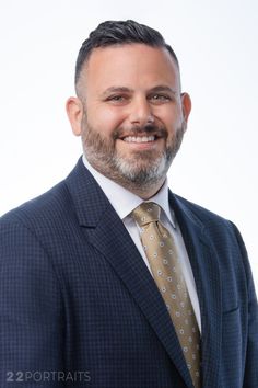 a man in a suit and tie smiling at the camera