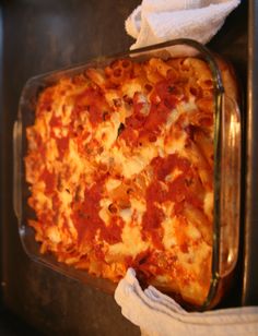 a casserole dish with cheese and tomato sauce in a glass pan on the stove