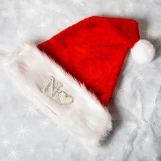 a red and white santa hat with the letter n on it's side sitting on a bed