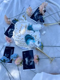 a white cake with blue frosting and flowers on it sitting on top of a table