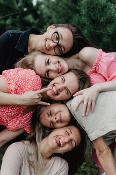 a group of young women standing next to each other in front of some trees and bushes