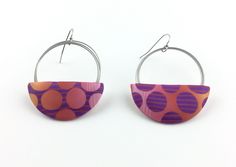 pair of purple and orange earrings with circular design on hoop ends, against white background